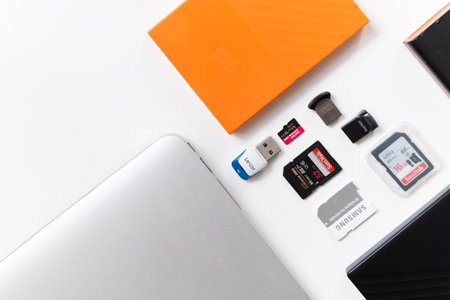 USA - 2021: Various digital data storage devices. Usb sticks, external hard drive, SD cards, mini and micro SD cards, laptop on white isolated background. Flat lay copy space textのeditorial素材