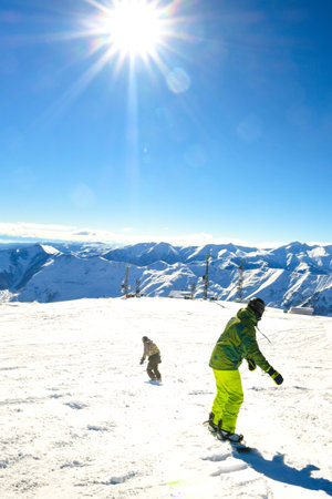 two friends buddies snowboarders back view ski downhill on holiday in ski resort have fun together in mountainsの写真素材