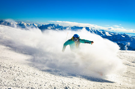 Professional skier at full speed ski downhill on fresh snow do carving in ski resort while training for competition in ski resort with mountains backgroundの写真素材