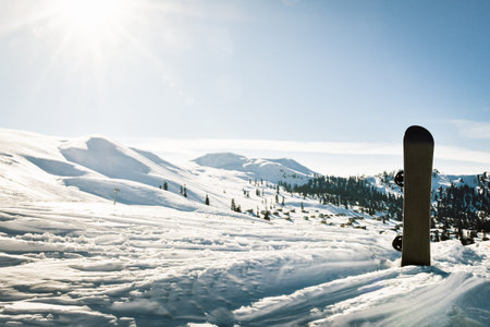 Black base of snowboard in a snow with white mountains in the background. Concept of new ski season.の写真素材