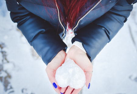 The heart made of snow in female hands. Kindness and care in snowy cold Valentin's Day. love background. kindness.の写真素材