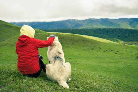 Female woman hiker sitting with big dog outdoors in mountains nature. Person petting dog. Young girl spending time with dog on leisureの写真素材