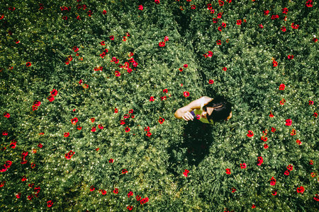 Top aerial girl smell flower in poppy field spring nature. Red green poppy flower field .Concept of woman wellness and freedomの写真素材