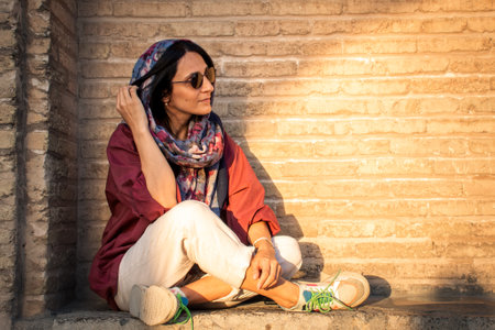 Modern brunette muslim woman sit wear hijab pose for portrait photo by historical landmark on vacationの写真素材