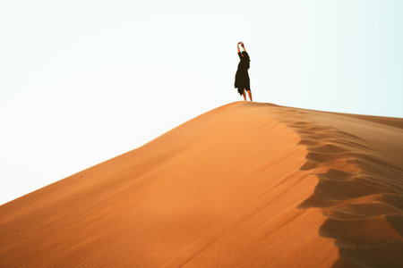 Woman enjoy sand dunes top in desert stretch arms pose . Travel lifestyle and wellness concept. Cinematic wanderlust backgroundの写真素材