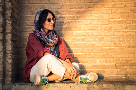 Modern brunette muslim woman sit wear hijab pose for portrait photo by historical landmark on vacationの写真素材