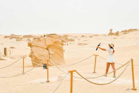 Female vlogger tourist content creator visit explore Fossil Dunes Structures in desert. Abu Dhabi, UAE. Famous travel destinationの写真素材