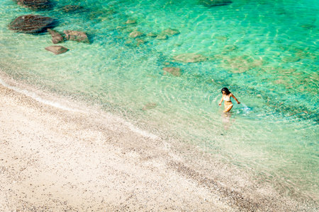 Aerial view isolated tourist woman in bikini walk on white sand beach alone in persian gulf Mirellas island. Musandam.Omanの写真素材