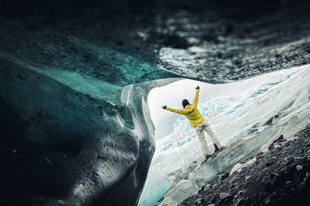 Tourist woman stand by beautiful FjallsjÃ¶kull glacier in Iceland in overcast day. Ice caves in Iceland. View from small gap caveの写真素材