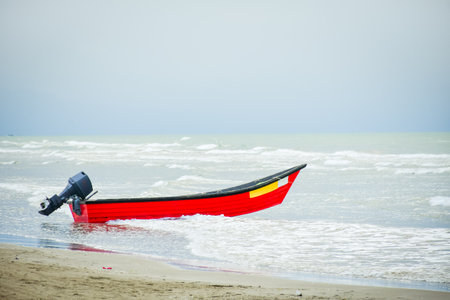 Red wooden motor boat on caspian sea shore in Bandar Anzali beach, north Iran, Gilan provinceの写真素材