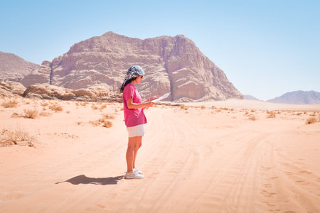 Young caucasian woman are lost and looking at a map.Girl Hiker alone in wadi rum desert looking at map for guidance in lost of her wayの写真素材