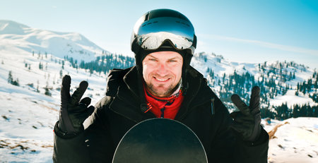 Close up portrait caucasian man with the reflection of snowed mountains, white slope and ski resort. A mountain range reflected in the ski mask. Portrait of man at the ski resortの写真素材