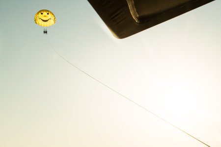 Three person family do para sailing in yellow parachute mid-air. Para-sailing and safety in water sportsの写真素材