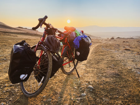 Loaded with bags red bicycle stands on side of road surrounded by mountains in countryside of VAshlovani national park. Bicycle touring holiday in Georgiaの写真素材