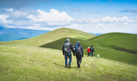 Young group of caucasian hikers hike in green mountains trail in caucasus region mount ikvlivi in springtime. Healthy lifestyle and leisure activities in spring timeの写真素材