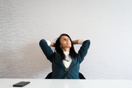 Young caucasian brunette business woman director in office lay back at work being thoughtful daydream about vacation with copy space text top wallの写真素材