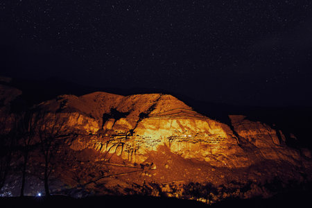 Starry night in famous tourist destination in Georgia-Illuminated Vardzia cave city. Romantic evening in wilderness under the stars.の写真素材