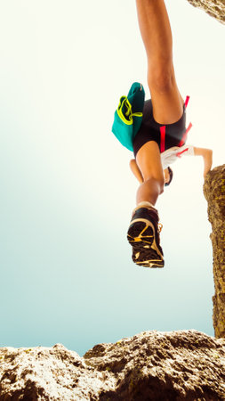 Low view female body step feet in air on hiking over rocks outdoors alone in hot sunny day outdoors....