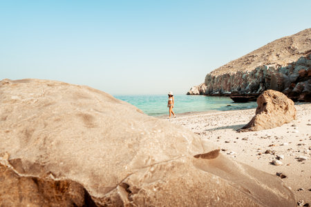 Aerial view isolated tourist woman in bikini walk on white sand beach alone in persian gulf Mirellas island. Musandam.Omanの写真素材