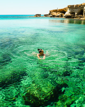 Woman swims in Northern cyprus Ayia napa bay shore with crystal clear blue mediterranean waters and...