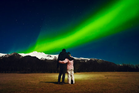 Romantic young caucasian couple together hug each other in cold night stand watch northern lights...