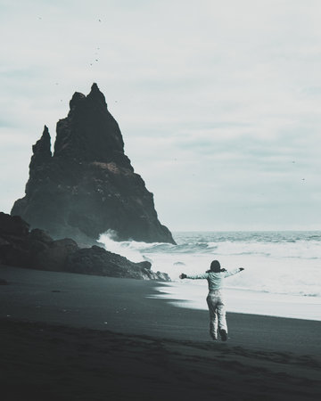 Caucasian tourist woman jumping of happiness - Icelandic touristic destination popular attraction - Reynisfjara black sand beach. Panoramic bannerの写真素材