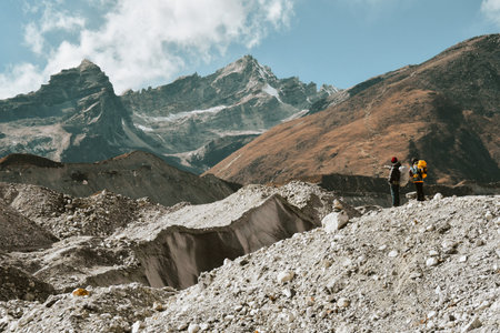 Two trekkers trekking in Himalayas mountains through Chola glacier pass to Gokyo Ri. Nepalese male guide leading tourist client in Sagarmatha national park official trek.の写真素材