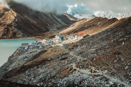 Two trekkers trekking in Himalayas mountains arrive to Gokyo Ri village. Nepalese male guide leading...
