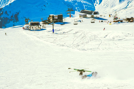 Dynamic picture of skier on the piste in Alps fall down hard in snow. Active winter holidays, skiing...
