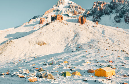 Bethlemi hut base camp with colorful tents in snow. Acclimatization and preparation concept. Climbing Mount Kazbek. Kazbegi municipality. Snowy Caucasus mountain panorama in sunny dayの写真素材