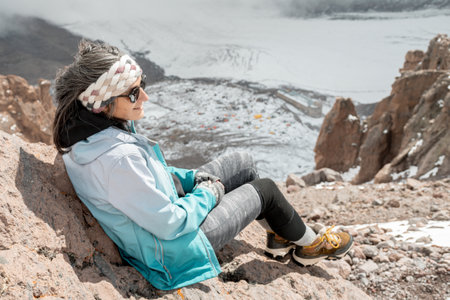 Woman climber sit over Bethlemi hut meteo station and Mount Kazbek base camp.Acclimatization day. Climbing Mount kazbek preparation conceptの写真素材