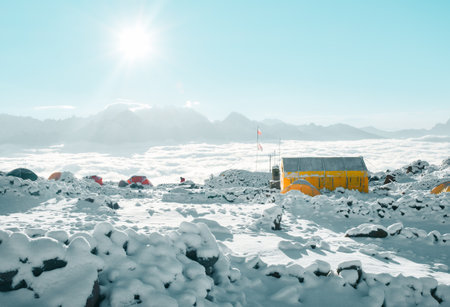 Climber surrounded by tents in Bethlemi hut base camp above clouds on sunny morning. Acclimatization and mountaineering concept. Climbing Mount Kazbek. Kazbegi municipality famous destinationの写真素材