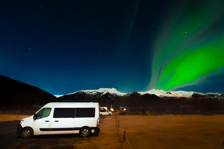 Campervan parked in Skaftafell campground with Aurora northern lights at night over snowy mountain...