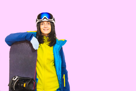Close up snowboarder woman wear blue suit goggles mask hat ski padded jacket cover mouth with snowboard isolated on plain pastel white space. Winter extreme sport snowboard weekend trip relax conceptの写真素材