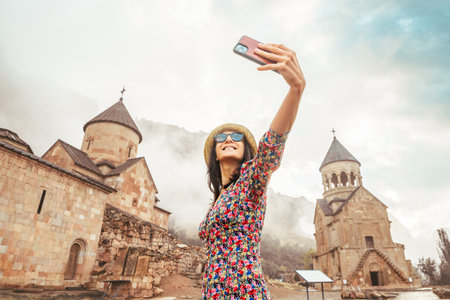 Happy excited female tourist takes a selfie photo against the background of the famous Noravank...