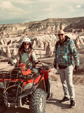 Happy couple man and woman on red quad. A group of people taking an ATV sunset tour around the valleys and balloons in Cappadocia.の写真素材