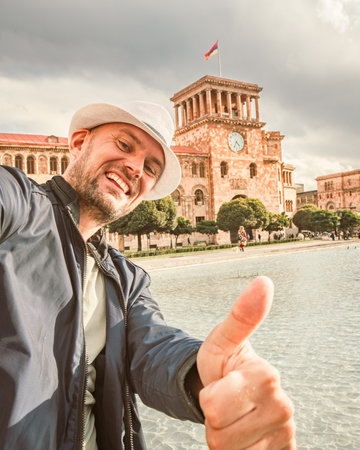 Middle aged male tourist stand by fountain show thumbs up in famous republic square in Yerevan,...