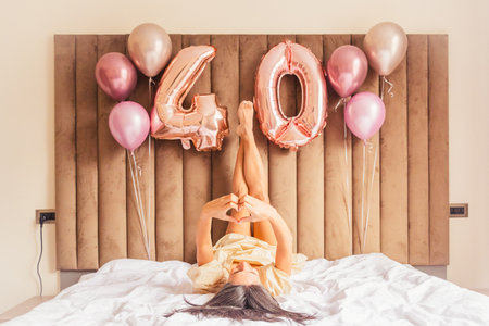 Pretty younger looking proud middle-age woman lay on bed pose celebrate forty years of age being proud healthy happy and confident. Mid-life perfection. Mature woman moderate make-up looking at cameraの写真素材