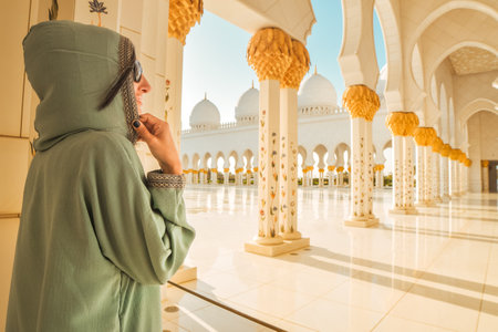a tourist girl in a muslim dress Abaya pose travel photo while travels through the Great Mosque of Sheikh Zayed in Abu Dhabiの写真素材