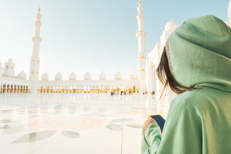 Sheikh Zayed Grand Mosque tour excursion or booking a visit concept.Female tourist visitor hold use phone post online travel photo check social media . Awe of iconic Islamic architecture in Abu Dhabiの写真素材