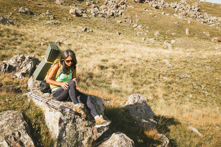Young female hiker backpacker woman touch her sore knee joint massage in pain at a downhill rocky road on trek or hike outdoorsの写真素材
