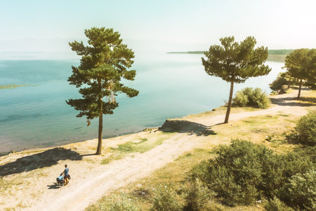 Aerial view solo cyclist bicycle touring stand by lake in hot summer day on summer cycling holidays....