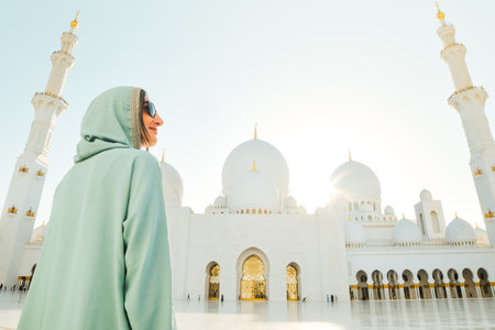 Abu Dhabi, UAE - april 25th, 2025: woman traveler wear stylish abaya sightseeing Sheikh Zayed Grand Mosque in Abu Dhabi on beautiful sunset. Free entrance mosque visit entrance famous destinationの写真素材