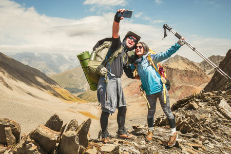 Happy couple of hikers taking selfie portrait on the top of the mountain - Smiling tourists enjoying summer day out - Boyfriend and girlfriend havingの写真素材