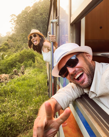 Happy excited passenger travel couple stand by doorstep enjoy popular train ride journey Kandy to Ella and admire Sri lanka lush jungle landscapes. Embrace freedom, curiosity, wonder asia travelの写真素材