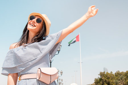 Happy young female tourist smile pose enjoy visiting Abu dhabi, UAE - Traveller girl taking portrait selfie with capital skyline background. Urban middle east city life travel attractions conceptの写真素材
