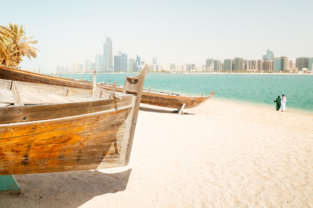 Abu Dhabi skyline and old traditional fishing boats in Heritage Village in Abu Dhabi in United Arab Emirates UAE. Couple tourist enjoy beach and visit sightseeing travel destination in UAEの写真素材