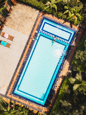 Top down view serene scene woman enjoying swim in private pool deep within Sri Lanka lush and isolated wilderness in topical forest jungles.Tranquil retreat offer peace, natural beauty. Perfect escapeの写真素材