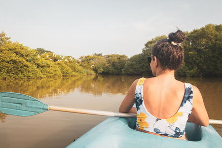 Back view woman sit in double blue kayak. Couple kayaks on calm waters of Tangalle Lagoon in...