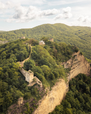 Aerial view ancient Bochorma fortress complex in Georgia surrounded by scenic Caucasus mountains. Medieval site features stone fortifications, domed church, panoramic views over Iori River valleyの写真素材